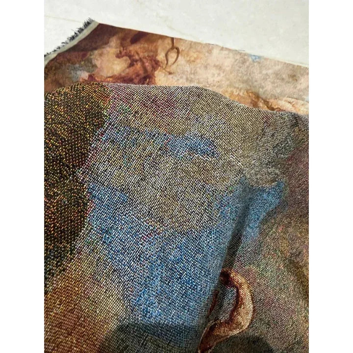 Folded real tapestry fabric showing small interlaced yarns and mixed colour tones